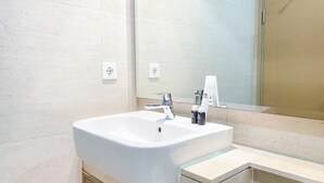 Une salle de bain moderne avec un lavabo blanc, un robinet chromé et un miroir au-dessus.