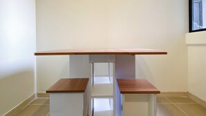 A simple, modern room with a wooden desk and two matching chairs. - Spacious And Comfy 2Br With Extra Room At Meikarta Apartment (Cikarang)