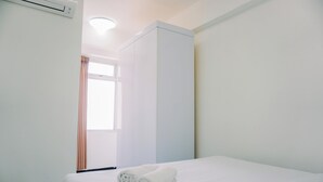 A hotel room with a bed, a wardrobe, and a window with curtains. - Cozy And Comfort Living 2Br Green Bay Pluit Apartment (Jakarta)