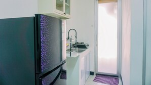 A compact kitchen with a refrigerator, a sink, and a cabinet above the counter. - Cozy And Comfort Living 2Br Green Bay Pluit Apartment (Jakarta)