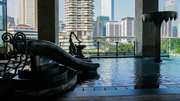 A rooftop pool with a slide, a fountain, and a view of the cityscape. - Gorgeous And Comfortable 1Br Sudirman Suites Apartment (Jakarta)