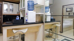 A modern kitchen with a water dispenser, a coffee machine, and a bar area with stools.