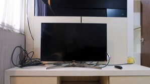 A TV on a wooden desk with a drawer below.