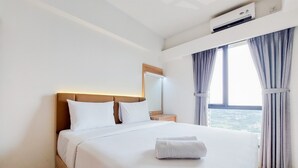 Een hotelkamer met een bed, een nachtkastje, een spiegel en een raam met gordijnen.
