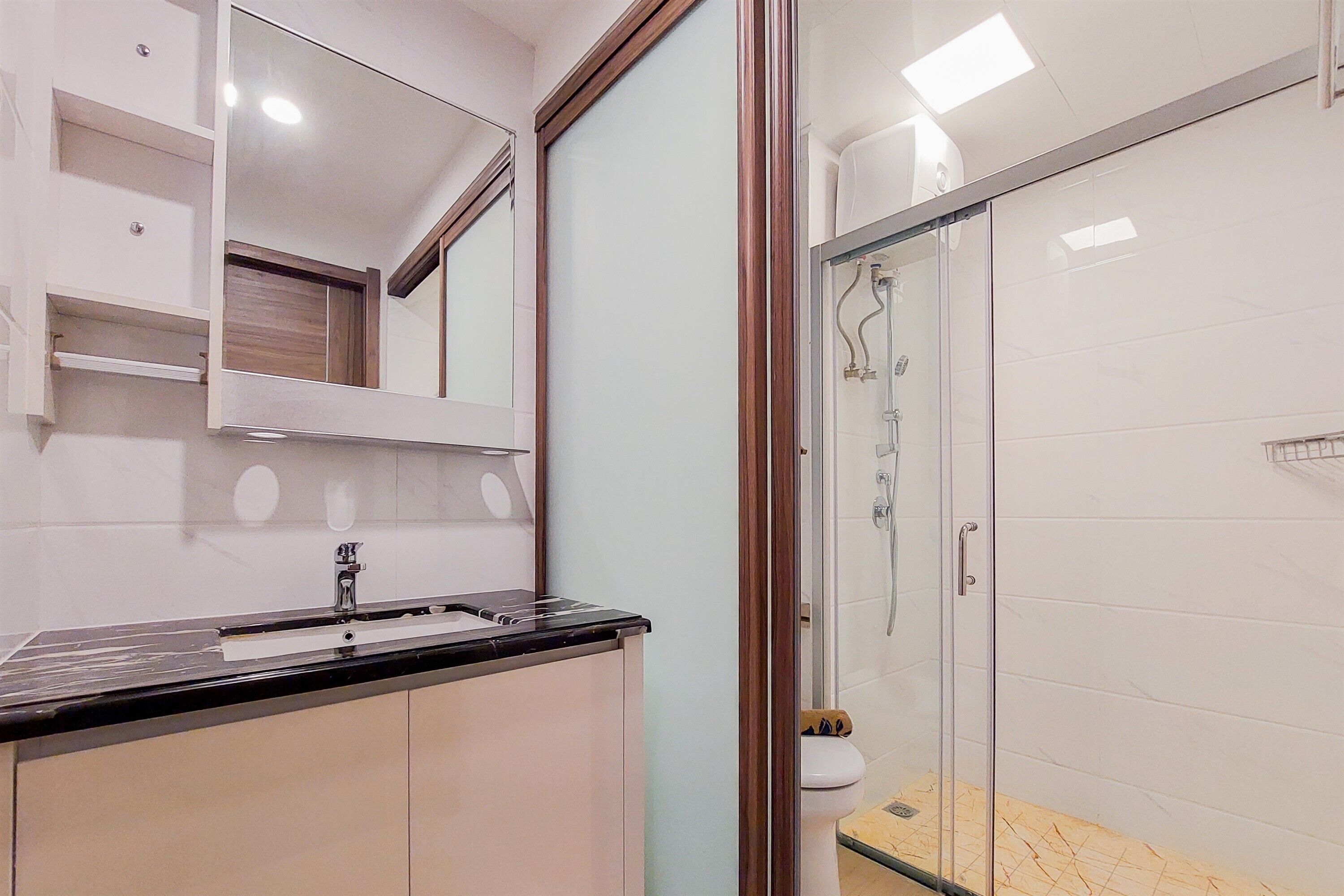 A modern bathroom with a glass shower enclosure, a sink with a black countertop, and a mirror above the sink.