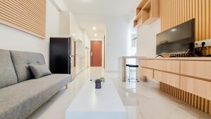 Een moderne woonkamer met een bank, een salontafel, een televisie en houten kasten.