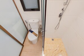 Ein Badezimmer mit Toilette, Dusche und Fenster.