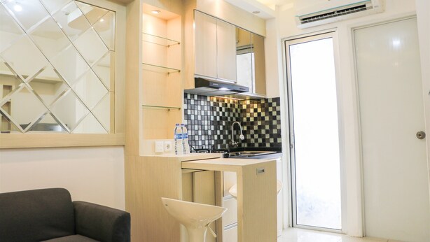 A compact kitchen with a modern design, featuring a black and white checkered backsplash, a built-in oven, and a small countertop. - Comfort And Modern 2Br At Bassura City Apartment (Jakarta)