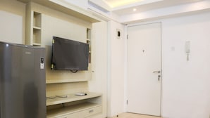 A compact kitchen with a refrigerator, a microwave, and a built-in TV shelf. - Comfort And Modern 2Br At Bassura City Apartment (Jakarta)