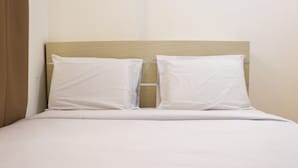 A bed with a wooden headboard and two white pillows. - Comfort And Modern 2Br At Bassura City Apartment (Jakarta)
