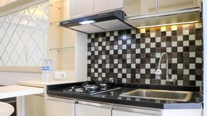 A kitchen with a gas stove, stainless steel sink, and a checkered backsplash. - Comfort And Modern 2Br At Bassura City Apartment (Jakarta)
