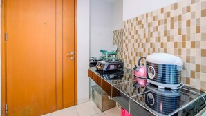 A kitchen with a wooden door, a tiled backsplash, and various appliances including a rice cooker and a mixer. - Good Choice Studio At Margonda Residence 5 Apartment (Depok)
