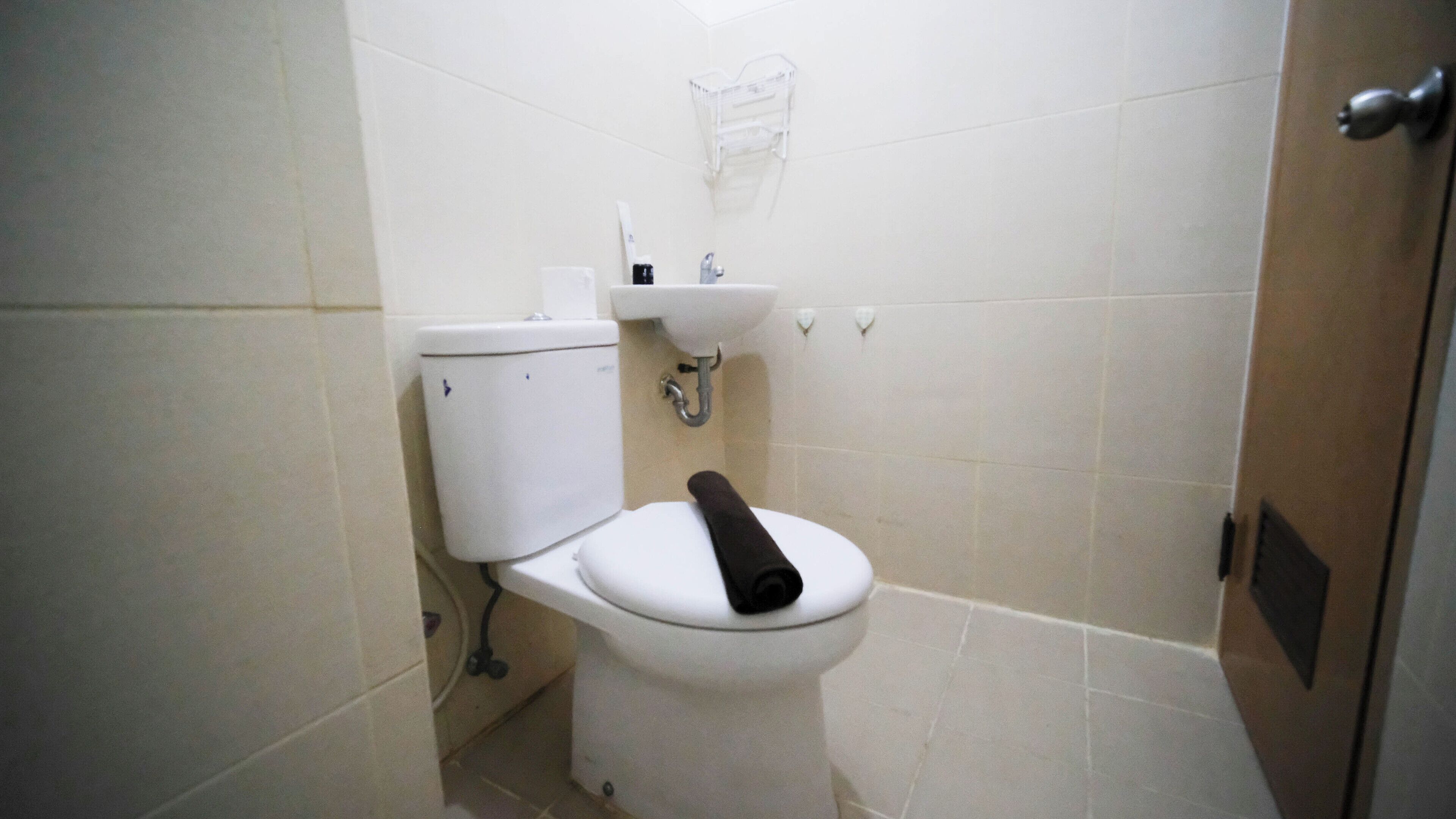 Ein kleines, sauberes Badezimmer mit Toilette, Waschbecken und Duschbereich.