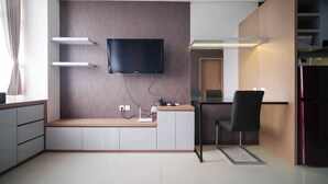 A modern kitchen with a built-in TV, a refrigerator, and a dining area. - Spacious 2Br Combine Unit At Bale Hinggil Apartment (Surabaya)