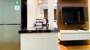 Une cuisine moderne équipée d’un réfrigérateur, d’un four à micro-ondes, d’une machine à café et d’un téléviseur à écran plat fixé au mur.