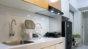 Een moderne keuken met een roestvrijstalen spoelbak, een afwasschaal, een zwarte koelkast en een inbouwoven.