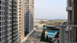Een hoog appartementencomplex met meerdere balkons en een zwembadgedeelte in de voorgrond.