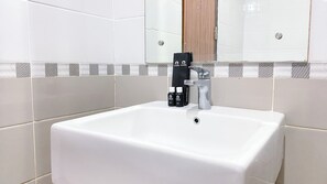 Ein weißes Waschbecken mit einem modernen Wasserhahn und einem schwarzen Reiseaccessoire auf der Ablagefläche.