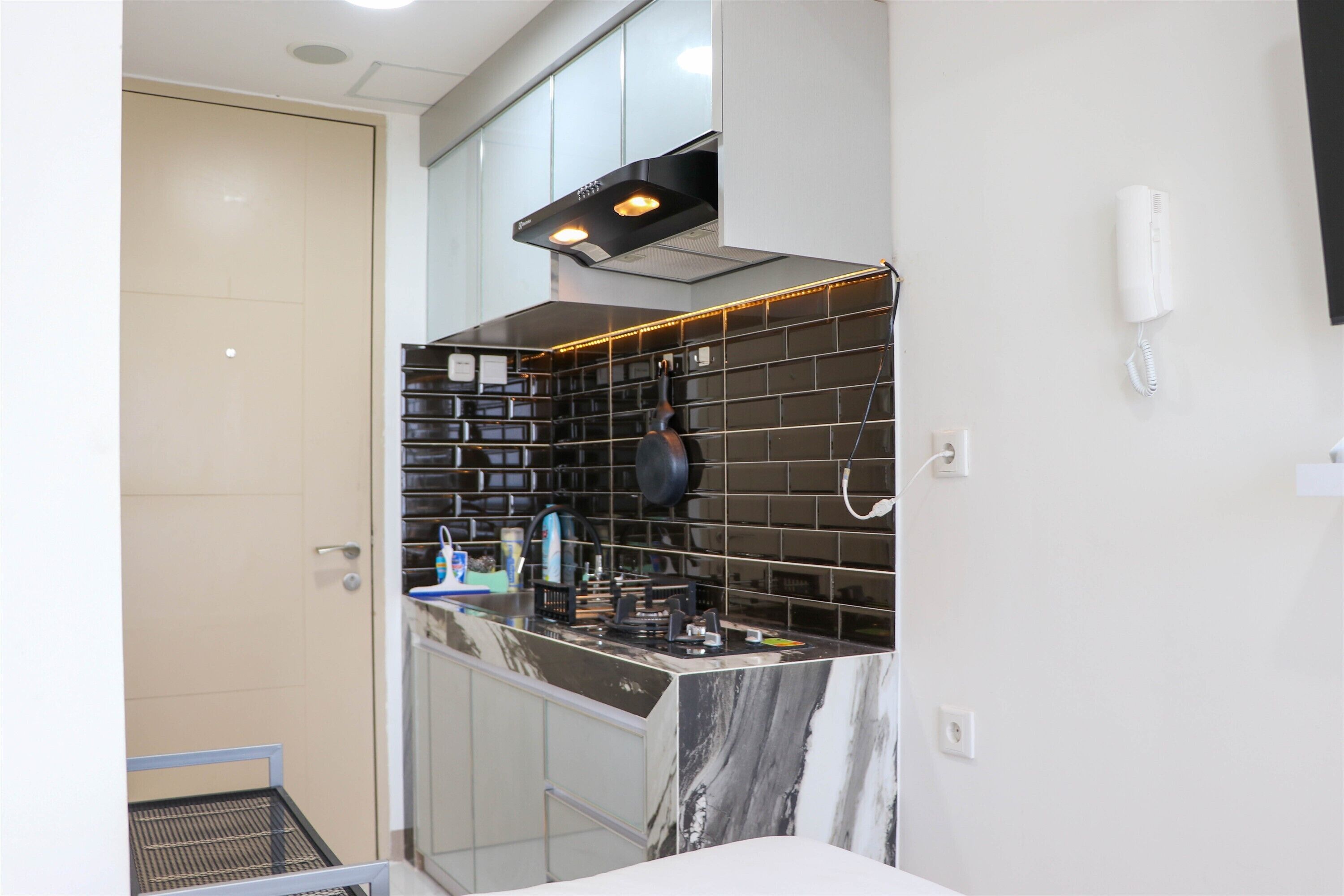 A modern kitchen with a marble countertop, black backsplash, and a built-in oven.