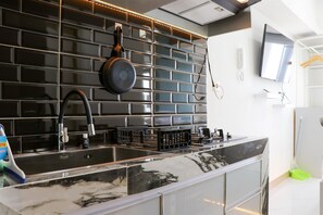 A modern kitchen with black tiled backsplash, stainless steel appliances, and a marble countertop. - Best Deal And Comfort Studio Tokyo Riverside Pik 2 Apartment (Teluknaga)