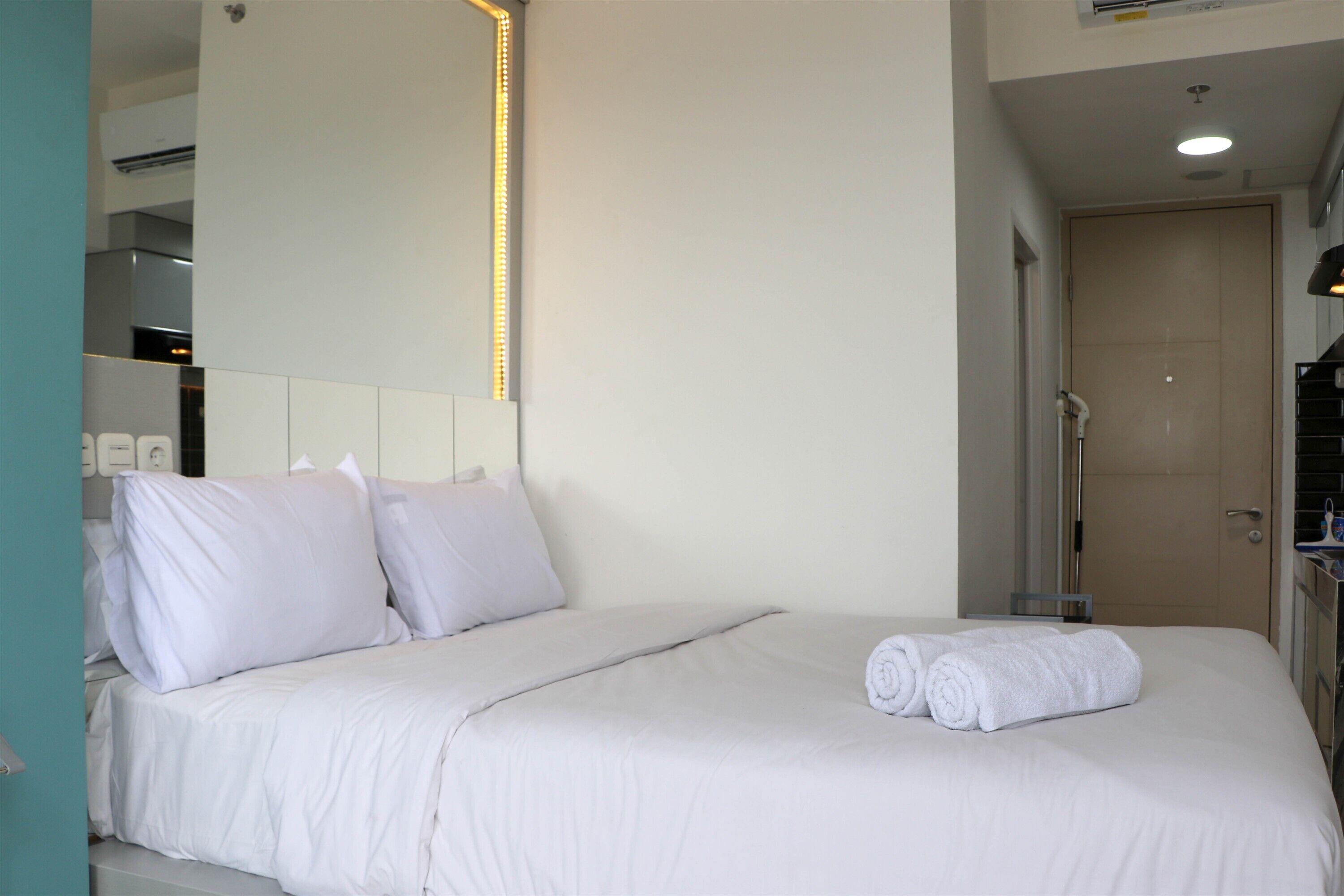 A hotel room with a bed, pillows, a neatly made bed, a towel, a shower area, and a bathroom with a toilet and sink.
