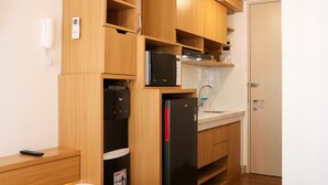 Une cuisine compacte avec des meubles en bois, un réfrigérateur noir, un four à micro-ondes et un distributeur d’eau.
