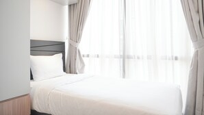 A hotel room with a large bed, a headboard, and sheer curtains. - Comfort And Elegant 2Br Sudirman Suites Apartment (Jakarta)