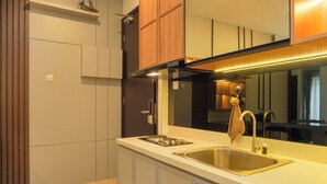 A modern kitchen with a stainless steel sink, wooden cabinets, and a large mirror above the countertop. - Comfort And Elegant 2Br Sudirman Suites Apartment (Jakarta)