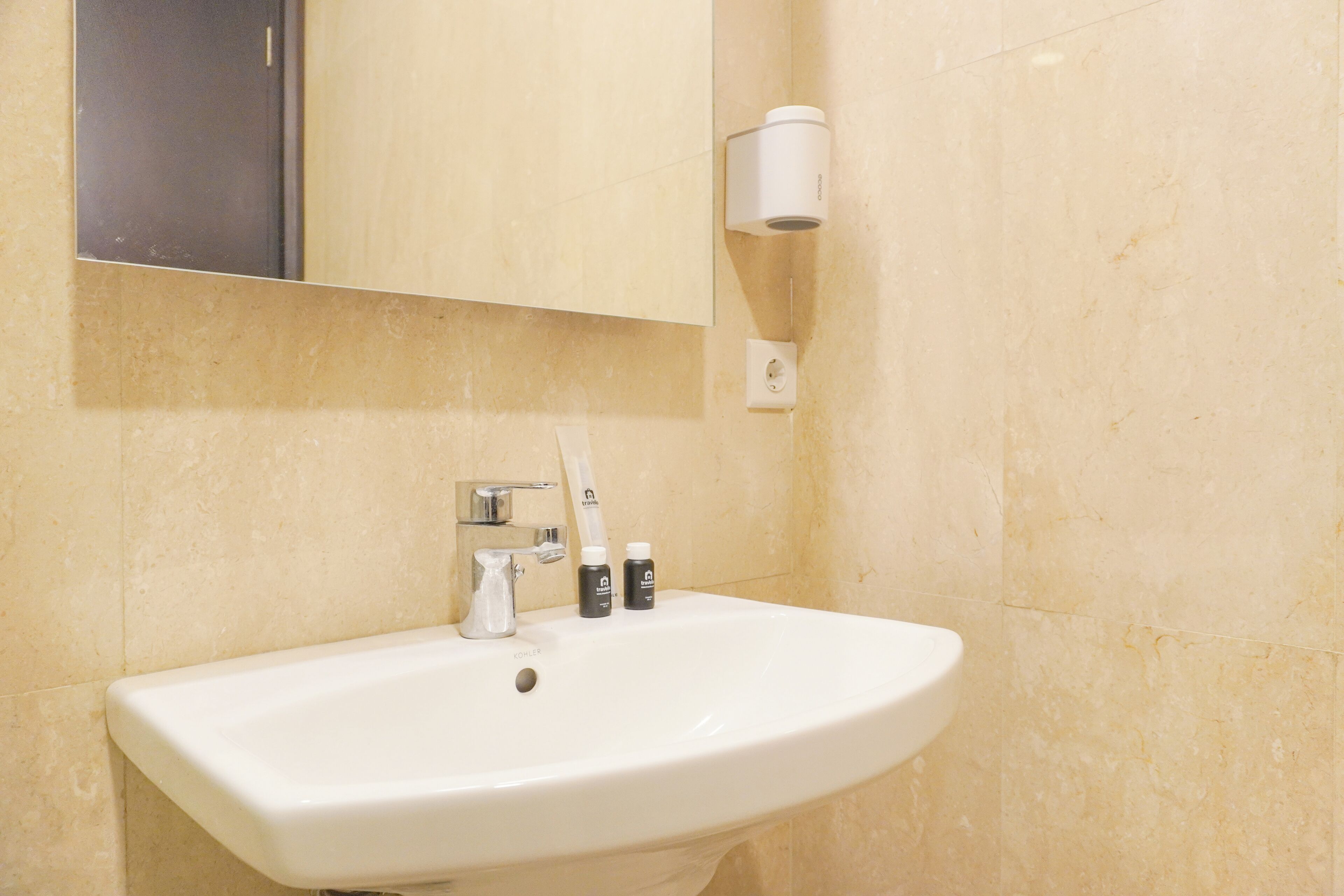 A bathroom with a white sink, a mirror, a towel dispenser, and a bottle of hand soap.