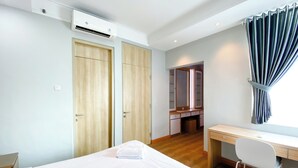 Ein Hotelzimmer mit Bett, Schreibtisch, Stuhl, Kleiderschrank und Spiegel.