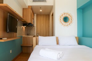 A hotel room with a bed, a TV, a wooden cabinet, and a bathroom.