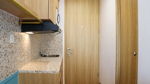 A compact kitchen with a countertop, sink, and wooden cabinets. - Modern And New Studio At Tokyo Riverside Pik 2 Apartment (Teluknaga)