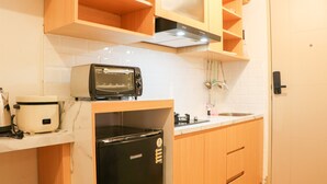 Une cuisine compacte équipée d’un four à micro-ondes, d’un cuiseur à riz et d’un réfrigérateur noir.