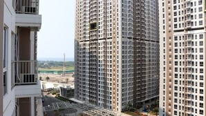 Un immeuble résidentiel de grande hauteur, doté de nombreux balcons, offrant une vue sur un chantier de construction et s’ouvrant sur un ciel dégagé.
