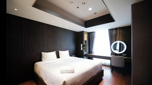 Ein modernes Hotelzimmer mit einem großen Bett, einem Schminktisch mit Spiegel und einem Fenster mit Vorhängen.