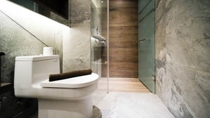 Ein modernes Badezimmer mit Toilette, einer Duschkabine aus Glas und Marmorwänden.