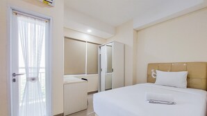 Une chambre d’hôtel avec un lit, une table de chevet, un miroir et une porte avec un rideau.