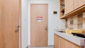 Une cuisine étroite avec des meubles en bois, un plan de travail blanc et un évier en acier inoxydable.