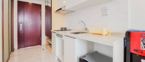 A modern kitchen with a built-in dishwasher, a sink, and a compact refrigerator.