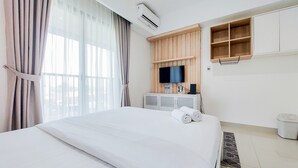 A hotel room with a bed, a TV, a wooden cabinet, and a window with curtains. - Comfort 1Br Without Living Room Bintaro Embarcadero Apartment (South Tangerang)
