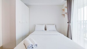 A minimalist hotel room with a neatly made bed, a wardrobe, and a window with curtains. - Comfort 1Br Without Living Room Bintaro Embarcadero Apartment (South Tangerang)