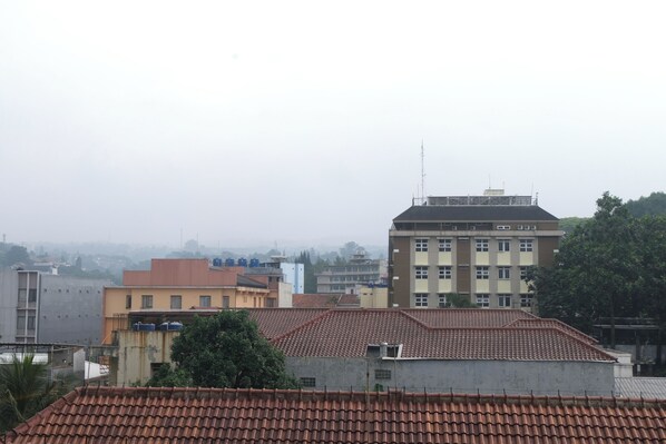 A multi-story building with a red-tiled roof, surrounded by other buildings. - Good Deal Studio Apartment At Parahyangan Residence (Bandung)