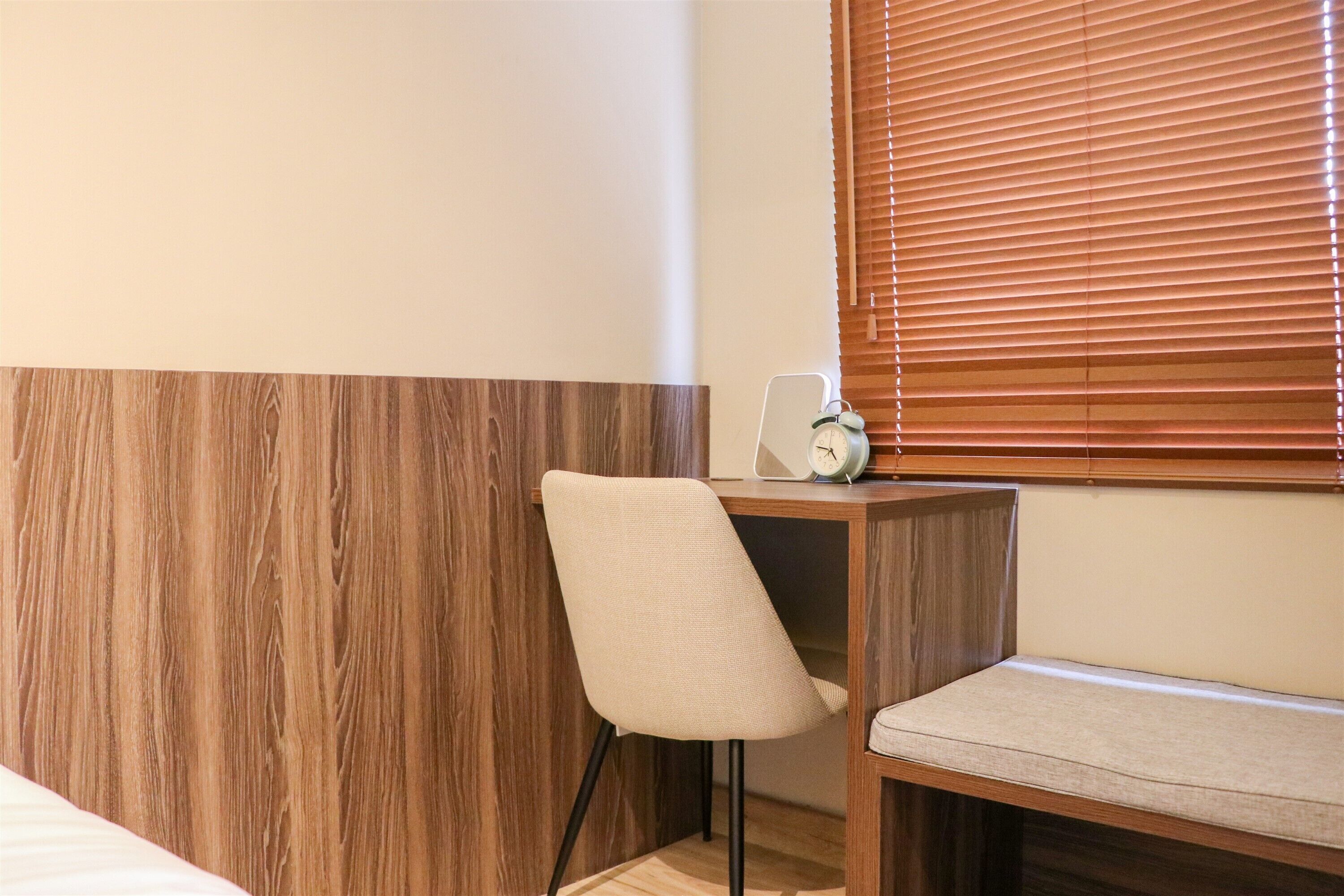 Ein Eckzimmer mit einer Wand in Holzoptik, einer gepolsterten Bank und einem kleinen Tisch mit einer Uhr.