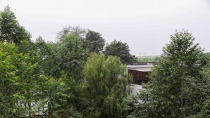 A modern building surrounded by dense greenery. - Simply Look Studio Room LRT City Jatibening Apartment (Bekasi)