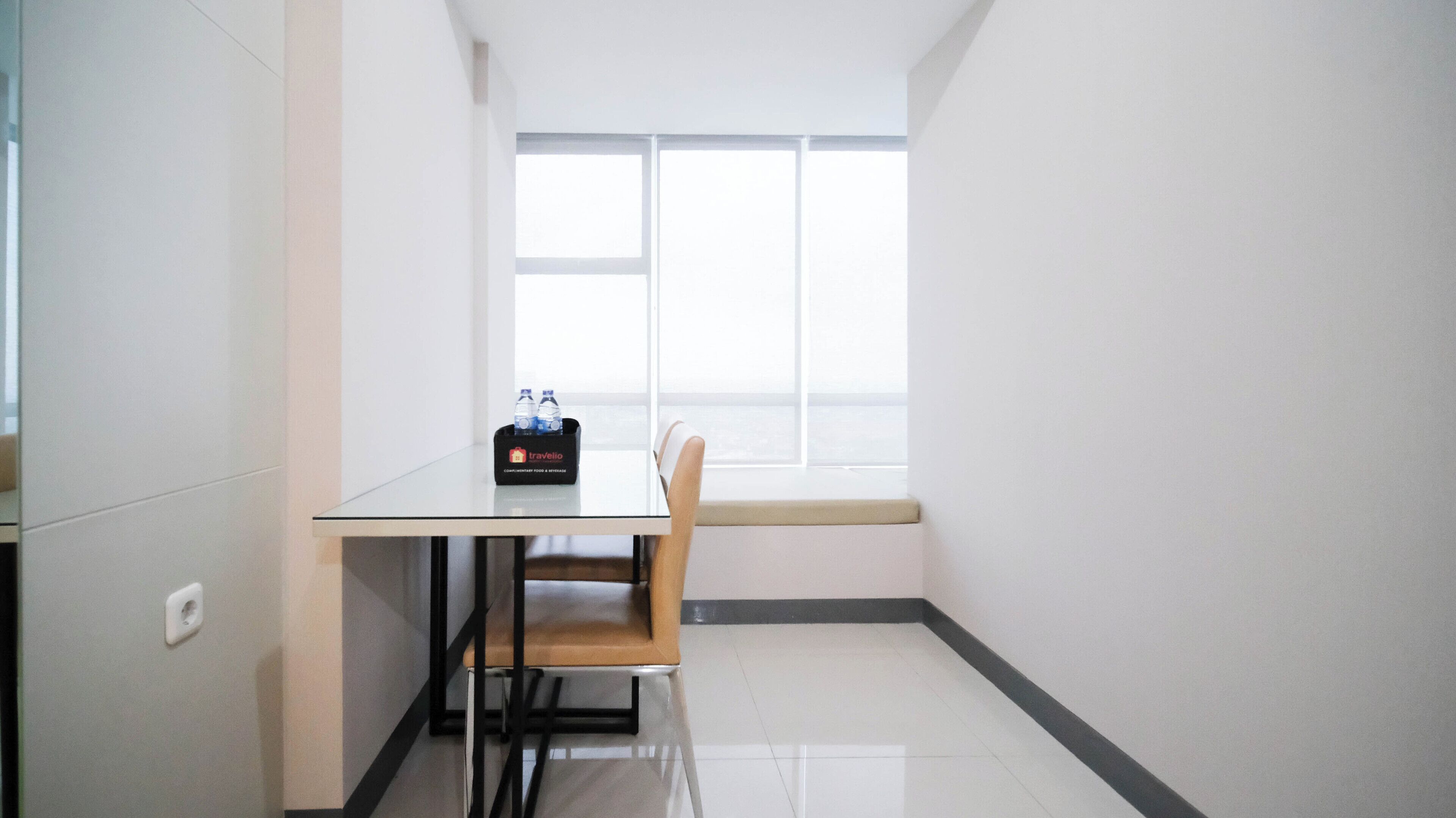 A small, clean room with a table, a chair, a window, and a water bottle holder.