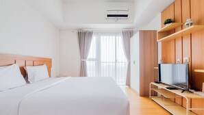 Een moderne hotelkamer met een groot bed, een televisie op een houten standaard en een raam met gordijnen.