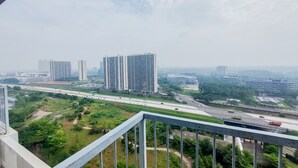Een hoog gebouw met meerdere verdiepingen, omgeven door groen en een snelweg.