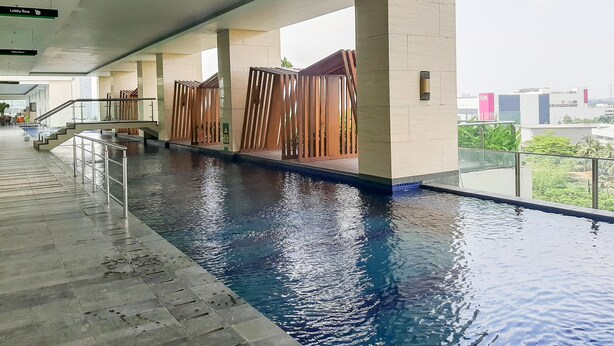 An indoor swimming pool with clear water, surrounded by stone walls and metal railings. - Cozy Stay And Good Deal Studio Apartment B Residence (Pagedangan)