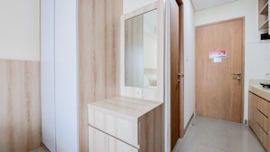 A hallway with a wooden vanity, a mirror, and a door with a sign. - Cozy Stay And Good Deal Studio Apartment B Residence (Pagedangan)