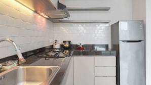 A modern kitchen with a stainless steel sink, a gas stove, a refrigerator, and white cabinetry. - 2Br Citralake Suites 2Nd Floor Comfy Easy Access Apartment (Jakarta)